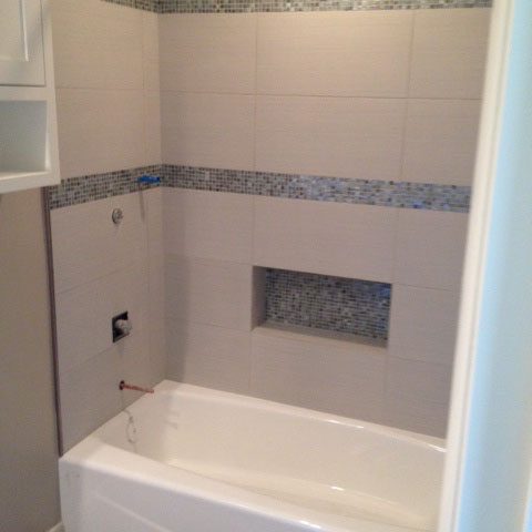 Beautiful new blue and white tile now surrounds the bath. Plumbing fixtures have yet to be replaced.